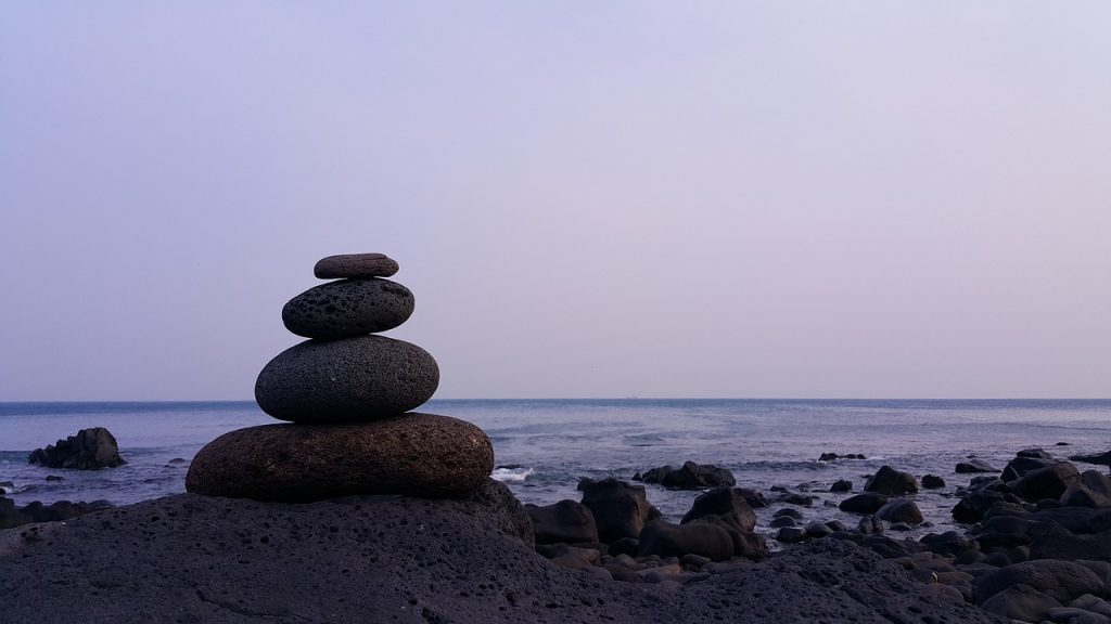 Stones balanced one ontop of another in foreground with sea in background.
