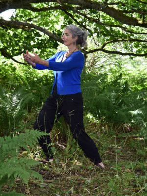 Woman with arms outstretched in front doing tai chi movements for wellbeing